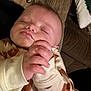 baby, sleeping, onesie, bear_pattern, hand, face, couch, pillow, cozy, infant, peaceful, rest, closeup, child, indoors, soft_texture, blanket, cute, portrait, relaxation