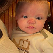 Alexander is registered to the contest to win money with this photo: adult, baby, blue_eyes, child, closeup, construction_vehicle_design, cozy, cute, face, head, indoor, infant, light_hair, person, portrait, skin, sweater, white_clothing, wooden_background, yellow_duck_patch