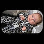 baby, infant, onesie, leopard_print, patterned_clothing, cushion, cloud_pattern, star_pattern, lying_down, curious_expression, indoor, portrait, child, cute, soft_toys, sleepwear, comfortable, young_child, face, small_hands