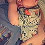 baby, infant, child, onesie, dinosaur_print, sleepy, person, hand, tattoo, clothing, holding, closeup, cute, skin, face, arm, casual, indoor, resting, toddler