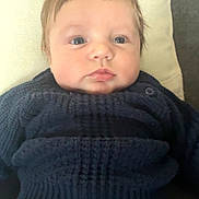 Marceau participe au concours pour gagner de l'argent avec cette photo : baby, infant, child, face, blue_eyes, sweater, navy, denim, pants, cushion, soft_furniture, indoor, portrait, cute, young, resting, closeup, head, person, clothing