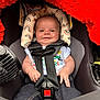 Andrew is registered to the contest to win money with this photo: baby, car_seat, smile, infant, child, seatbelt, clothing, fabric, red_blanket, headrest, rainbow_pattern, safety, cute, happy, small_hands, jeans, white_shirt, indoor, person, closeup