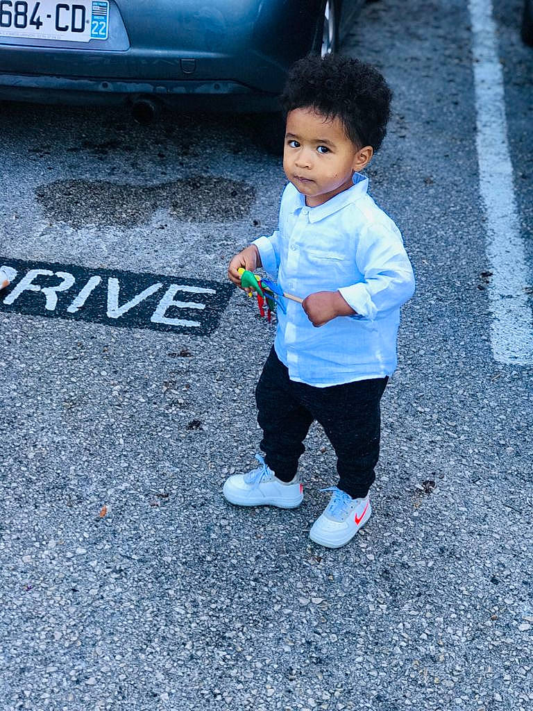 Arthur participe au concours pour gagner de l'argent avec cette photo : asphalt, automotive_design, automotive_exterior, automotive_lighting, automotive_tire, bumper, car, electric_blue, footwear, motor_vehicle, person, recreation, road, road_surface, shoe, sidewalk, sneakers, t_shirt, toddler, vehicle_door