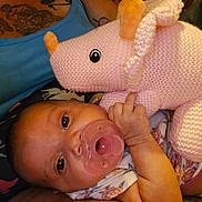 Annilynn is registered to the contest to win money with this photo: baby, pacifier, plushie, knitted_toy, pink, rhino, infant, tattoos, adult, tank_top, lying_down, close_up, hand, cute, child, person, fabric, pattern, indoor, cozy