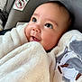 baby, infant, blanket, car_seat, cute, smile, face, child, cozy, soft_texture, eyelashes, closeup, warm, adorable, comfort, indoors, animal_embroidery, happy, wrapped, toddler