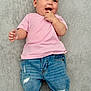 baby, child, smiling, pink_shirt, blue_jeans, rolled_jeans, barefoot, lying_down, gray_background, happy, infant, cute, casual_clothing, portrait, indoor, person, small_child, face, hand, feet