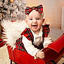 baby, child, smiling, red_bow, red_dress, sleigh, christmas_tree, holiday, decorations, plaid, white_shirt, fluffy_cushion, indoors, festive, happy, portrait, cute, seasonal, holiday_decor, sitting