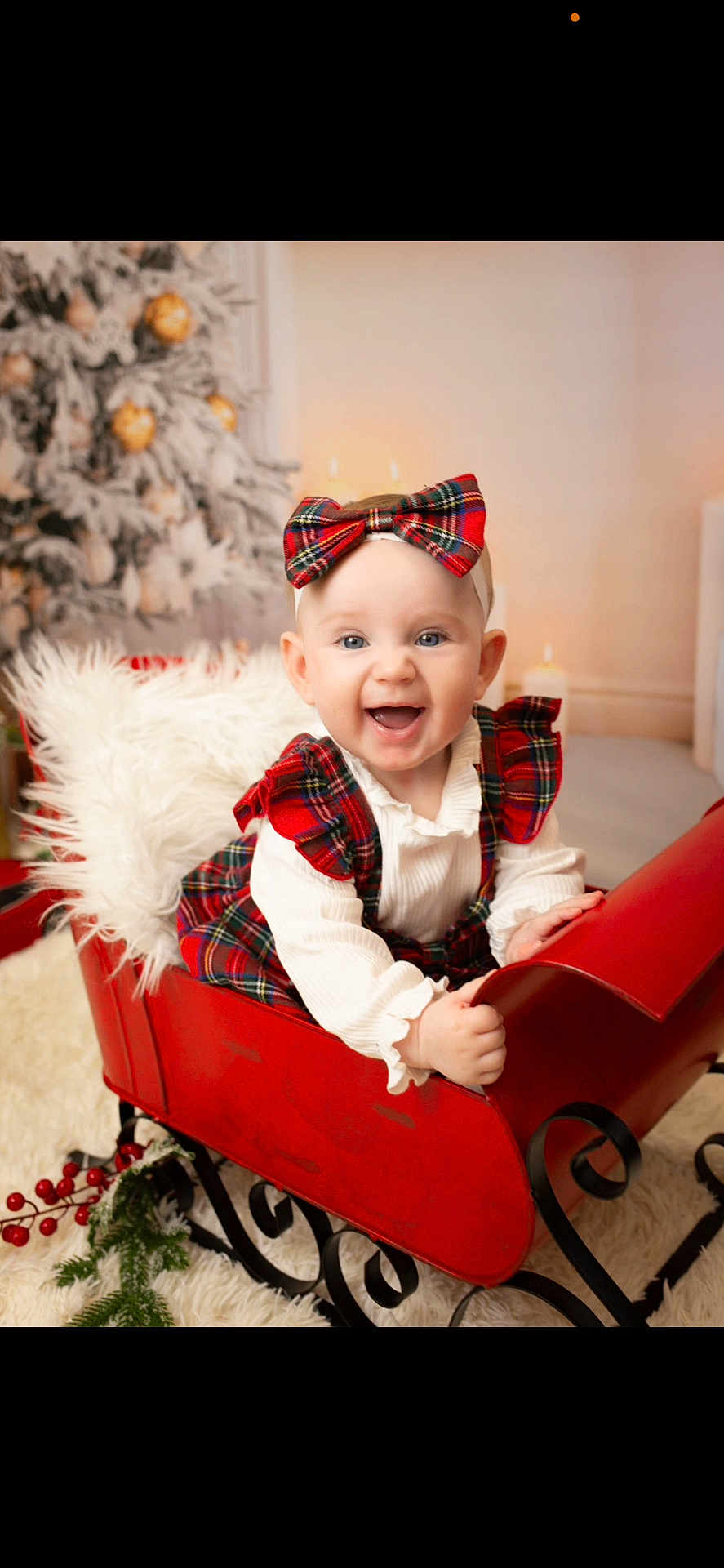 Ayla is registered to the contest to win money with this photo: baby, child, smiling, red_bow, red_dress, sleigh, christmas_tree, holiday, decorations, plaid, white_shirt, fluffy_cushion, indoors, festive, happy, portrait, cute, seasonal, holiday_decor, sitting
