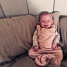 Aurora Elowen is registered to the contest to win money with this photo: baby, smile, blanket, couch, pillow, infant, child, happy, indoors, portrait, seated, cozy, soft, cute, young_child, face, clothing, home, relaxing, wrapped