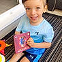 Kassim Menassel participe au concours pour gagner de l'argent avec cette photo : child, boy, smiling, blue_shirt, blue_shorts, toy, book, indoor, rug, play, happy, sitting, person, short_hair, bright_eyes, casual_clothing, under_armour, floor, home, cute