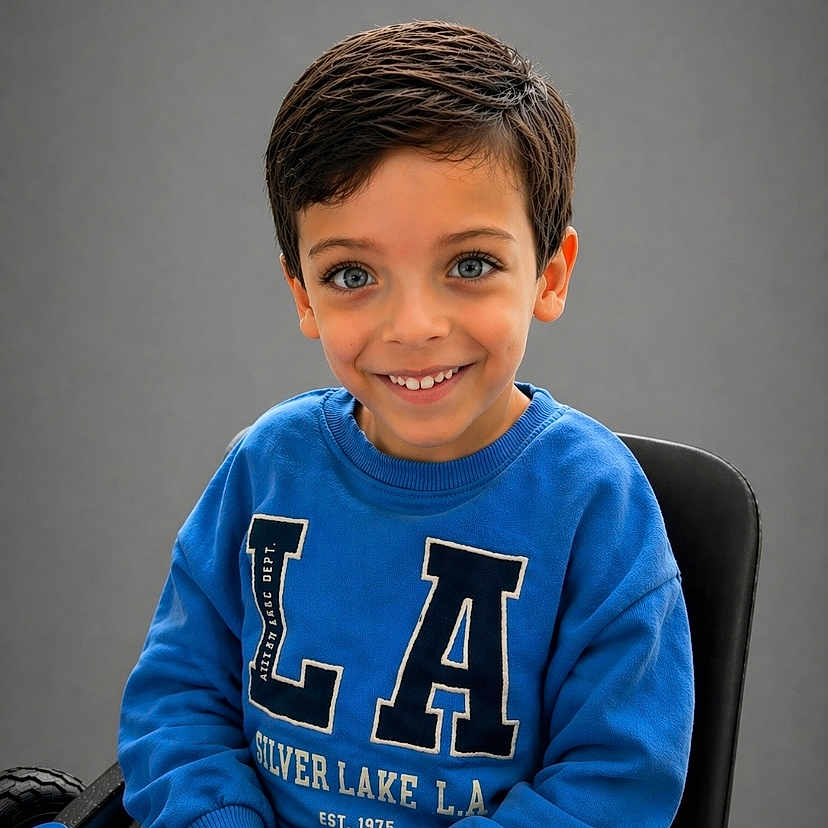 Isaak Menassel a rejoint le concours — aidez-le/la à gagner de superbes lots ! child, boy, smiling, portrait, blue_sweatshirt, sitting, chair, short_hair, indoor, casual_clothing, happy, cute, face, young, person, studio, background, youth, looking_at_camera, hands