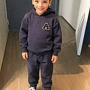 Isaak Menassel a rejoint le concours — aidez-le/la à gagner de superbes lots ! child, boy, smiling, hoodie, sweatpants, sneakers, indoor, hallway, wooden_floor, casual_clothing, standing, happy, young, portrait, fashion, footwear, person, cute, full_body, light