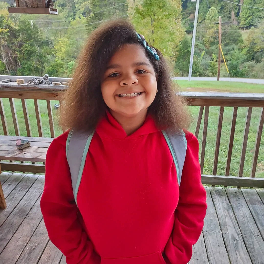 Jazzlyn is registered to the contest to win money with this photo: brown_hair, event, formal_wear, fun, grass, happy, jewellery, joy, leisure, outdoor_furniture, person, plant, recreation, school_uniform, sitting, sleeve, smile, t_shirt, tree, trunk