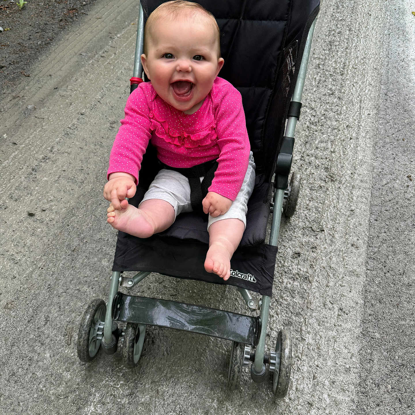 Riley is registered to the contest to win money with this photo: alloywheel, baby, car, city, clothing, face, happy, head, machine, pants, person, photography, plant, portrait, road, spoke, street, stroller, urban, wheel