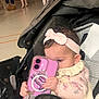Charlie is registered to the contest to win money with this photo: baby, infant, stroller, smartphone, pink, headband, blanket, toy, children, group, indoor, floor, dress, hand, seat, portrait, candid, accessory, playtime, event
