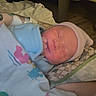 Elias is registered to the contest to win money with this photo: newborn, baby, infant, sleeping, portrait, face, knit_cap, blanket, swaddle, cozy, indoors, bed, adult, arm, tattoo, nursery, resting, peaceful, close_up, photography