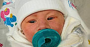 Elias is registered to the contest to win money with this photo: newborn, baby, infant, child, portrait, face, pacifier, white_hat, blanket, swaddled, hospital, bedding, closeup, looking_at_camera, cozy, blue, white, sleepwear, indoors, photography