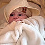 baby, infant, blanket, hat, hoodie, knit_hat, beige, cream, soft_texture, cozy, wrapped, cute, child, face, portrait, warm_clothing, indoor, comfort, sleepy, snuggled