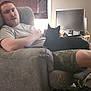 Mowmow joined the competition — help win amazing prizes! man, cat, chair, laptop, monitor, indoor, casual, relaxed, shorts, gray_shirt, black_cat, technology, furniture, living_room, seated, beard, curtains, remote_control, carpet, window