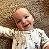 Rowan is registered to the contest to win money with this photo: baby, smiling, infant, carpet, onesie, animal_print, goat, cute, happy, face, child, indoors, playful, portrait, lying_down, cozy, young, skin, expression, person
