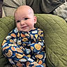 baby, child, onesie, clothing, smile, face, cushion, quilted, green, comfort, cute, pattern, food_illustration, infant, happy, indoors, portrait, relaxed, seated, cozy