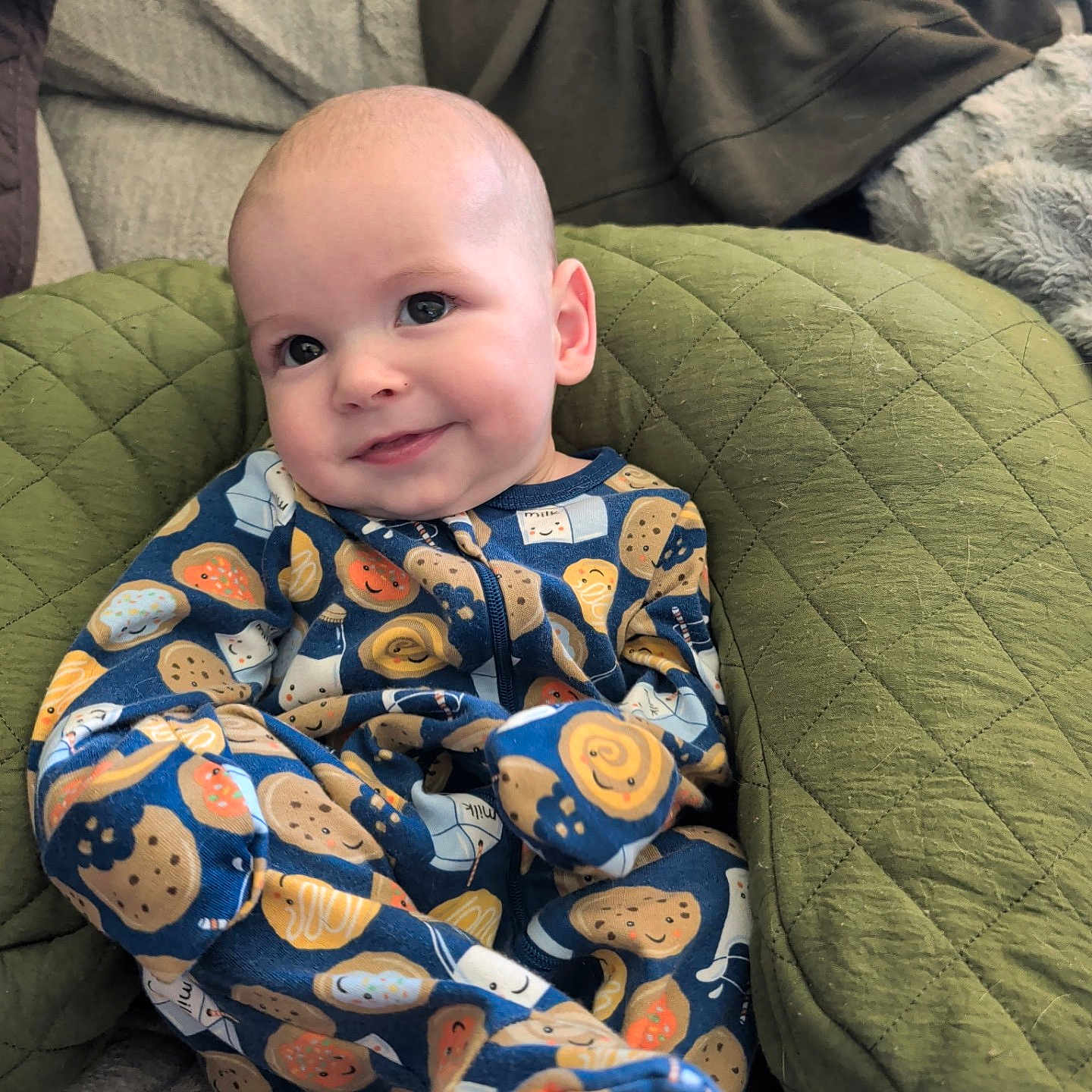 Rowan joined the competition — help win amazing prizes! baby, child, onesie, clothing, smile, face, cushion, quilted, green, comfort, cute, pattern, food_illustration, infant, happy, indoors, portrait, relaxed, seated, cozy