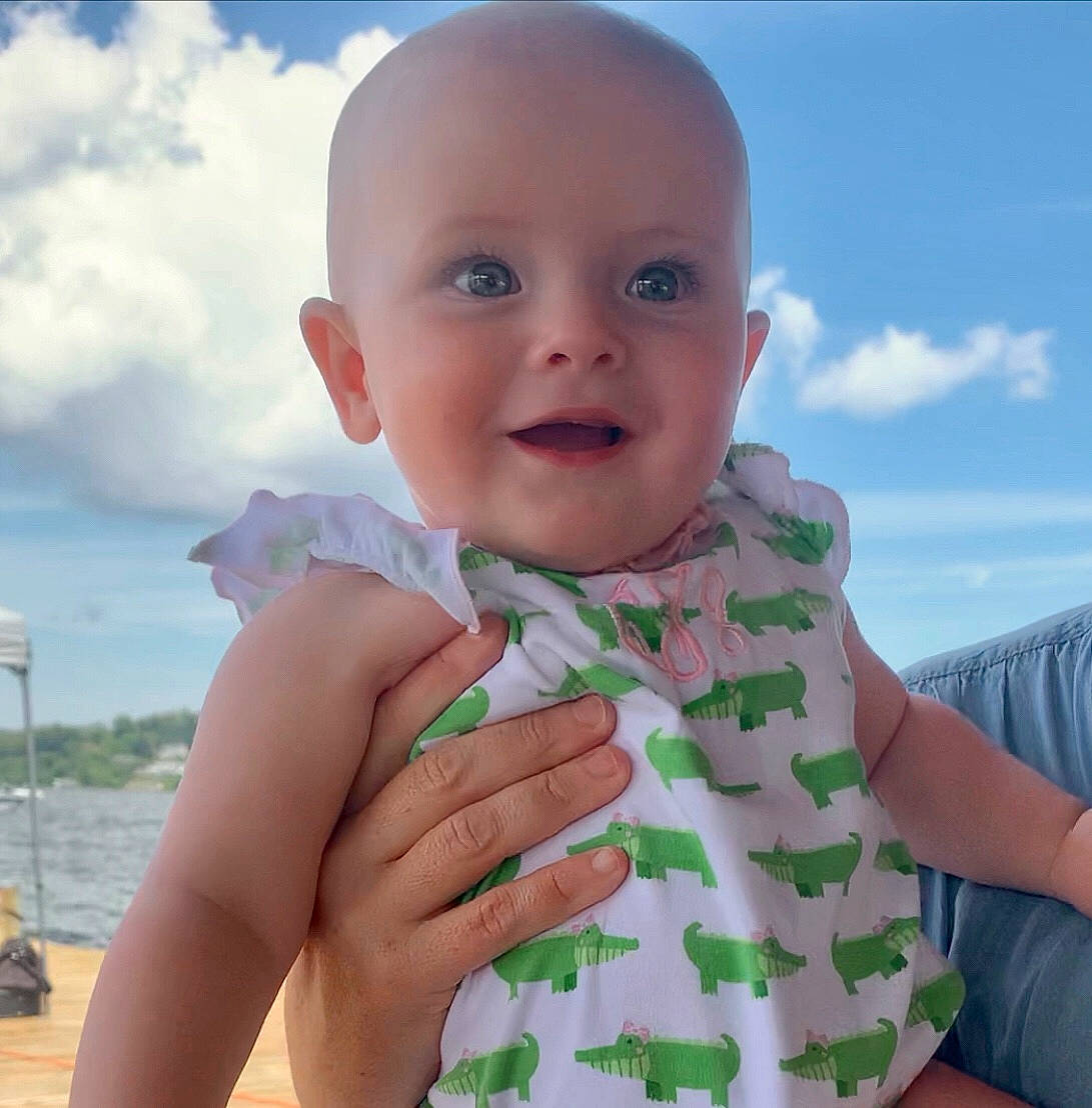 Cora is registered to the contest to win money with this photo: baby, baby_laughing, baby_toddler_clothing, cloud, finger, fun, gesture, grass, hand, happy, iris, nail, people_in_nature, person, skin, sky, sleeve, smile, standing, thumb