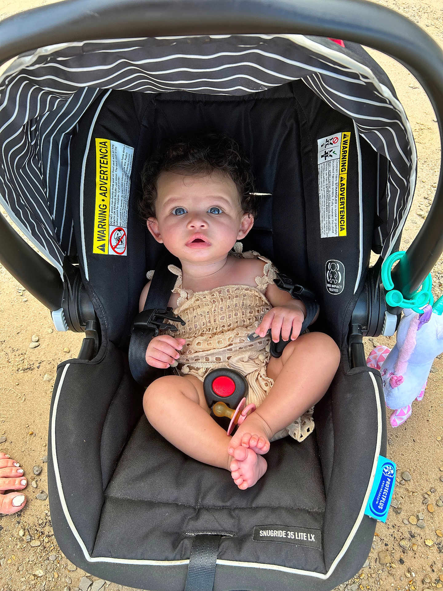 Eriyah joined the competition — help win amazing prizes! baby, infant, car_seat, pacifier, curly_hair, blue_eyes, sand, outdoor, toy, plush_toy, black_car_seat, straps, warning_label, foot, skin, cute, child, seated, summer, daylight