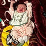 baby, infant, sleeping, pink_clothing, bib, blanket, cartoon, dog, face, hands, feet, cute, lying_down, stretching, cozy, soft_texture, home, child, newborn, expression