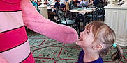 Tilly is registered to the contest to win money with this photo: child, girl, mascot, pink, smile, happy, restaurant, indoor, carpet, people, table, chair, costume, interaction, fun, celebration, curly_hair, casual_clothing, light, decor