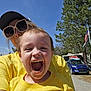 Wesley is registered to the contest to win money with this photo: child, adult, yellow_shirt, sunglasses, cap, outdoor, smile, happy, sunny, tree, car, blue_sky, person, face, laughing, nature, recreation, vehicle, camping, joy