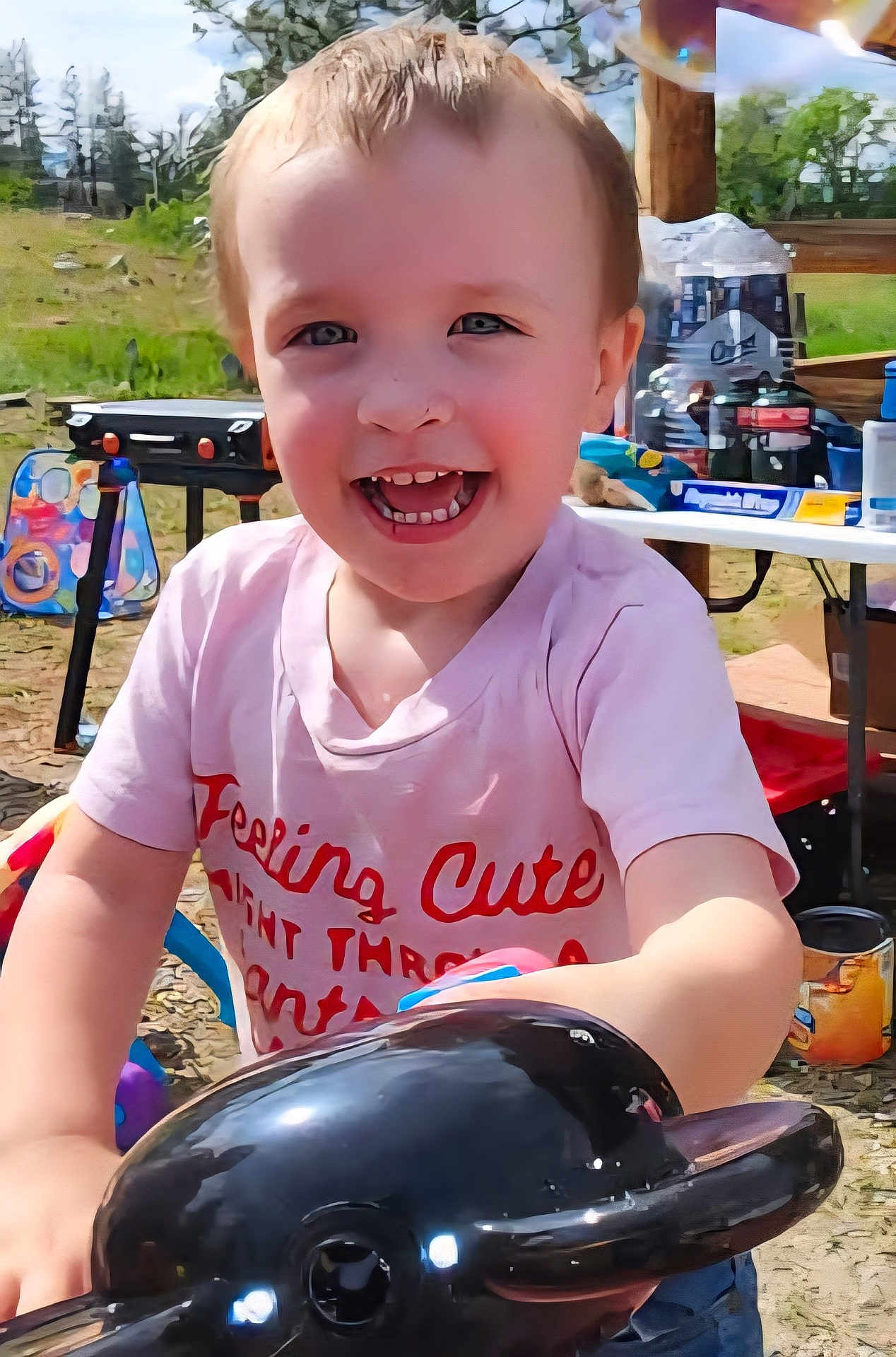 Wesley is registered to the contest to win money with this photo: child, toddler, smiling, outdoor, toy, dolphin, play, picnic, greenery, table, plastic, daylight, happy, casual, fun, summer, cute, clothing, face, person