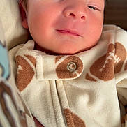 Rylan is registered to the contest to win money with this photo: baby, child, clothing, cozy, cute, face, fleece, football, hand, indoors, infant, newborn, pattern, portrait, skin, sleepy, small_fingers, snug, soft_fabric, warm