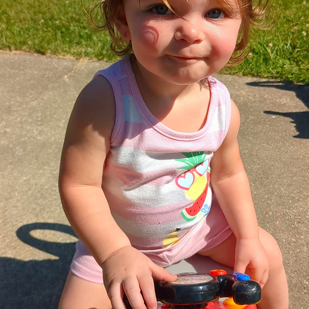 Angel is registered to the contest to win money with this photo: bodypart, child, face, female, finger, girl, grass, hand, head, lawn, machine, outdoors, person, photography, plant, playarea, portrait, transportation, vehicle, wheel