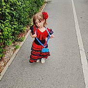 Ilona participe au concours pour gagner de l'argent avec cette photo : child, girl, dress, red, black, flower, hair_accessory, playful, outdoor, path, greenery, bushes, pavement, footwear, posing, young, fashion, accessory, smile, casual