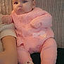 baby, infant, pink_clothing, knitted, socks, cute, child, person, indoor, cozy, texture, couch, seated, portrait, soft_lighting, small_hands, warm, cute_expression, babysuit, adorable