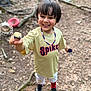 Elias joined the competition — help win amazing prizes! child, boy, smiling, outdoor, dirt, sticks, leaves, necklace, tshirt, sportswear, white_pants, red_socks, black_shoes, toy, happy, face, short_hair, playing, nature, ground