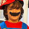 child, costume, mario, hat, mustache, red, blue, yellow, face, smile, indoor, hair, childhood, playful, portrait, fun, dressup, person, cute, happy