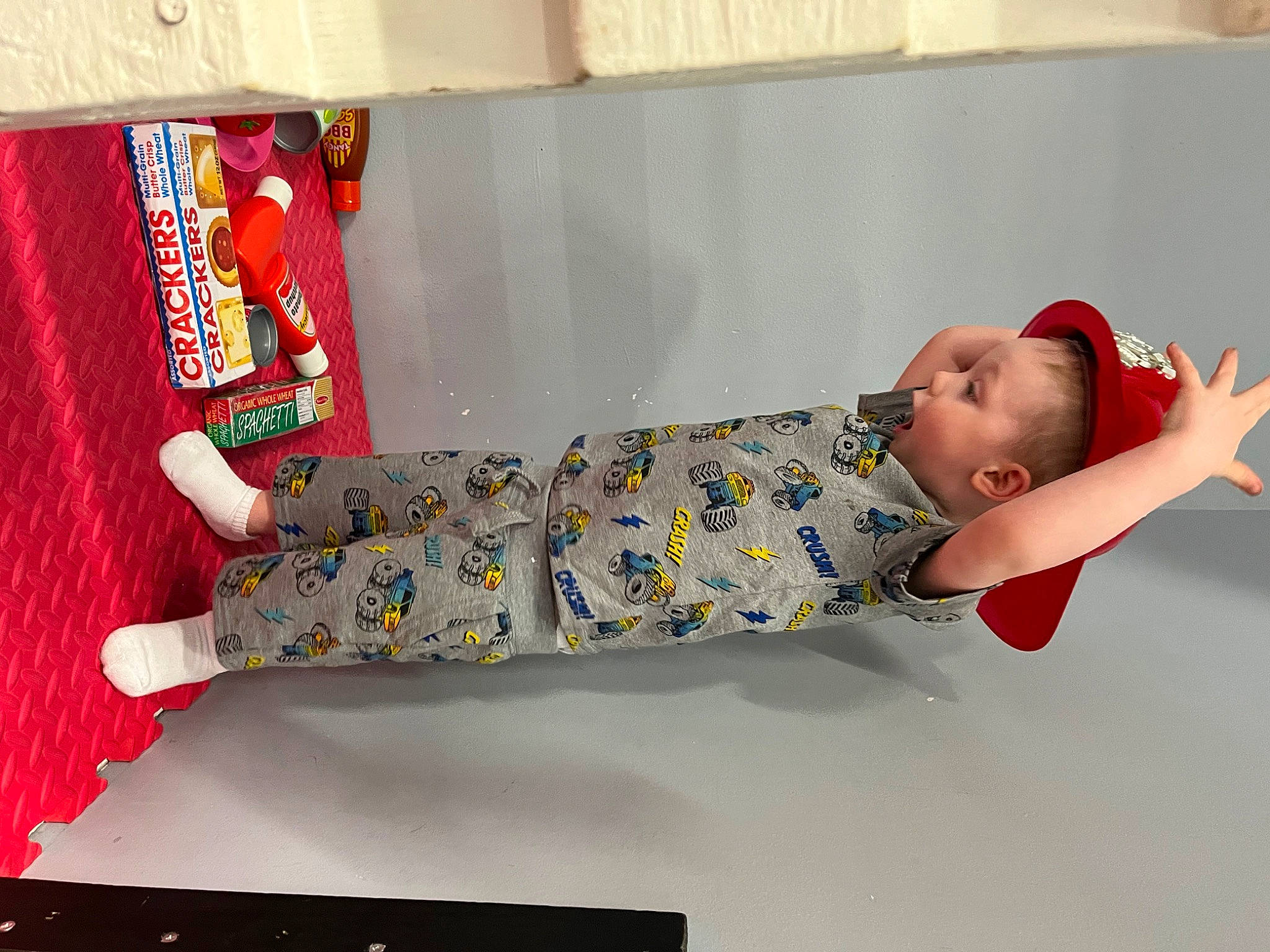 Graham is registered to the contest to win money with this photo: baby, baby_products, baby_toddler_clothing, baby_toys, carmine, child, comfort, elbow, fashion_design, flooring, human_leg, linens, pattern, person, play, room, sandal, sitting, stuffed_toy, thigh