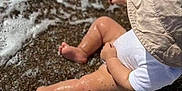 Kaïs Habeche participe au concours pour gagner de l'argent avec cette photo : toddler, child, beach, water, waves, pebbles, hat, white_clothing, toy, bucket, summer, outdoor, sand, legs, barefoot, sunlight, play, sea, shore, vacation