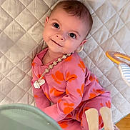 Calliope is registered to the contest to win money with this photo: baby, child, smiling, pink_clothing, orange_flower_pattern, onesie, quilted_mat, toy, indoor, floor, cute, happy, infant, person, portrait, playtime, soft_toys, head, eyes, skin