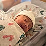 newborn, baby, infant, sleeping, blanket, hat, hospital, bassinet, footprint_pattern, cozy, wrapped, cute, peaceful, portrait, soft_light, indoors, closeup, baby_clothes, face, resting