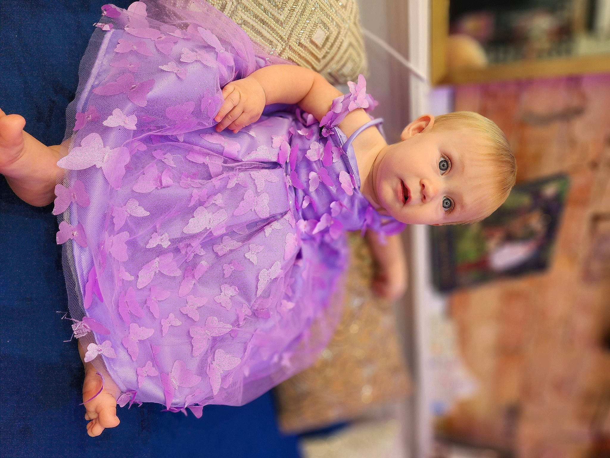 Wednesday is registered to the contest to win money with this photo: baby_toddler_clothing, child, doll, dress, embellishment, event, fashion_accessory, fashion_design, fun, happy, headpiece, human_body, magenta, person, pink, plant, purple, shelf, surprise, toddler