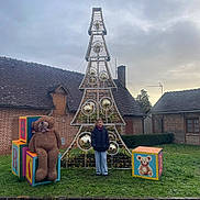 Alaïs a rejoint le concours — aidez-le/la à gagner de superbes lots ! child, smiling, jacket, jeans, christmas_tree, lights, ornaments, teddy_bear, alphabet_blocks, grass, outdoor, brick_buildings, cloudy_sky, holiday, festive, reflection, person, toy, winter_clothing, garden