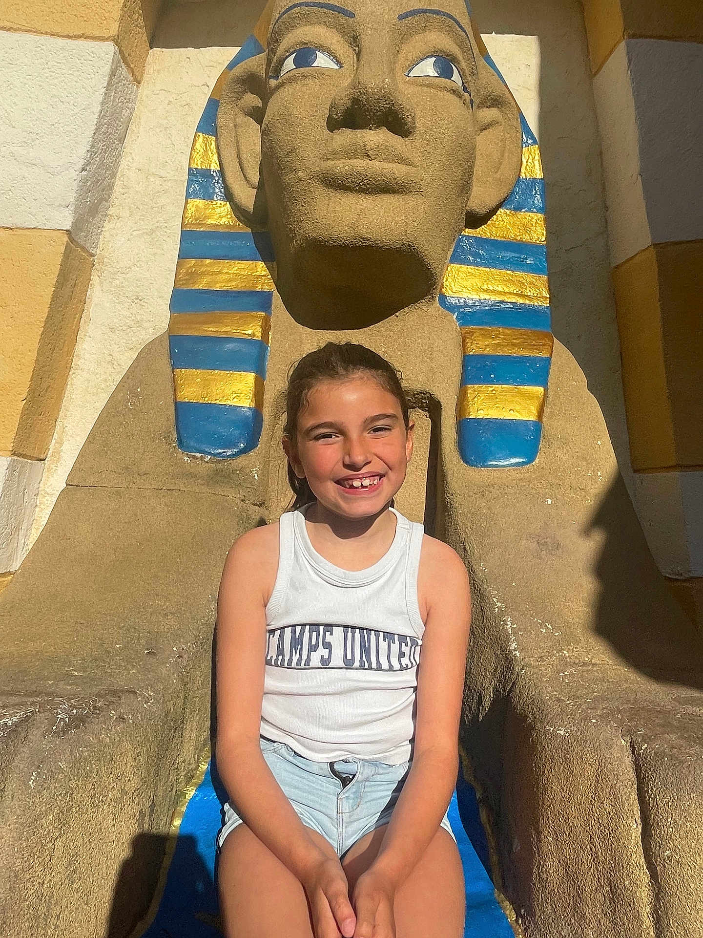 Alaïs participe au concours pour gagner de l'argent avec cette photo : child, smiling, girl, tank_top, shorts, outdoor, statue, egyptian, pharaoh, sunlight, shadow, concrete, blue, yellow, face, person, summer, happy, tourist, vacation