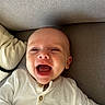 baby, infant, smiling, happy, face, person, white_clothing, buttoned_shirt, couch, fabric, texture, indoor, child, portrait, head, skin, eyes, mouth, cute, lying_down