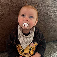 Ava is registered to the contest to win money with this photo: animal_face, baby, bib, carpet, cartoon, child, clothing, cute, expression, face, hands, indoor, infant, looking_up, pacifier, pigtails, portrait, soft_lighting, sweater, young_child
