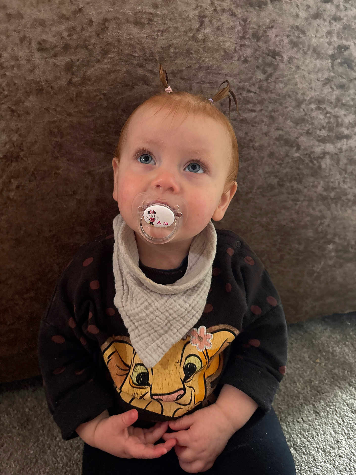 Ava is registered to the contest to win money with this photo: animal_face, baby, bib, carpet, cartoon, child, clothing, cute, expression, face, hands, indoor, infant, looking_up, pacifier, pigtails, portrait, soft_lighting, sweater, young_child