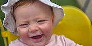 Ava is registered to the contest to win money with this photo: baby, baby_clothing, child, cute, face, fun, greenery, happy, hat, high_chair, infant, laughter, outdoor, person, pink_shirt, portrait, seated, smiling, sun_hat, yellow_chair