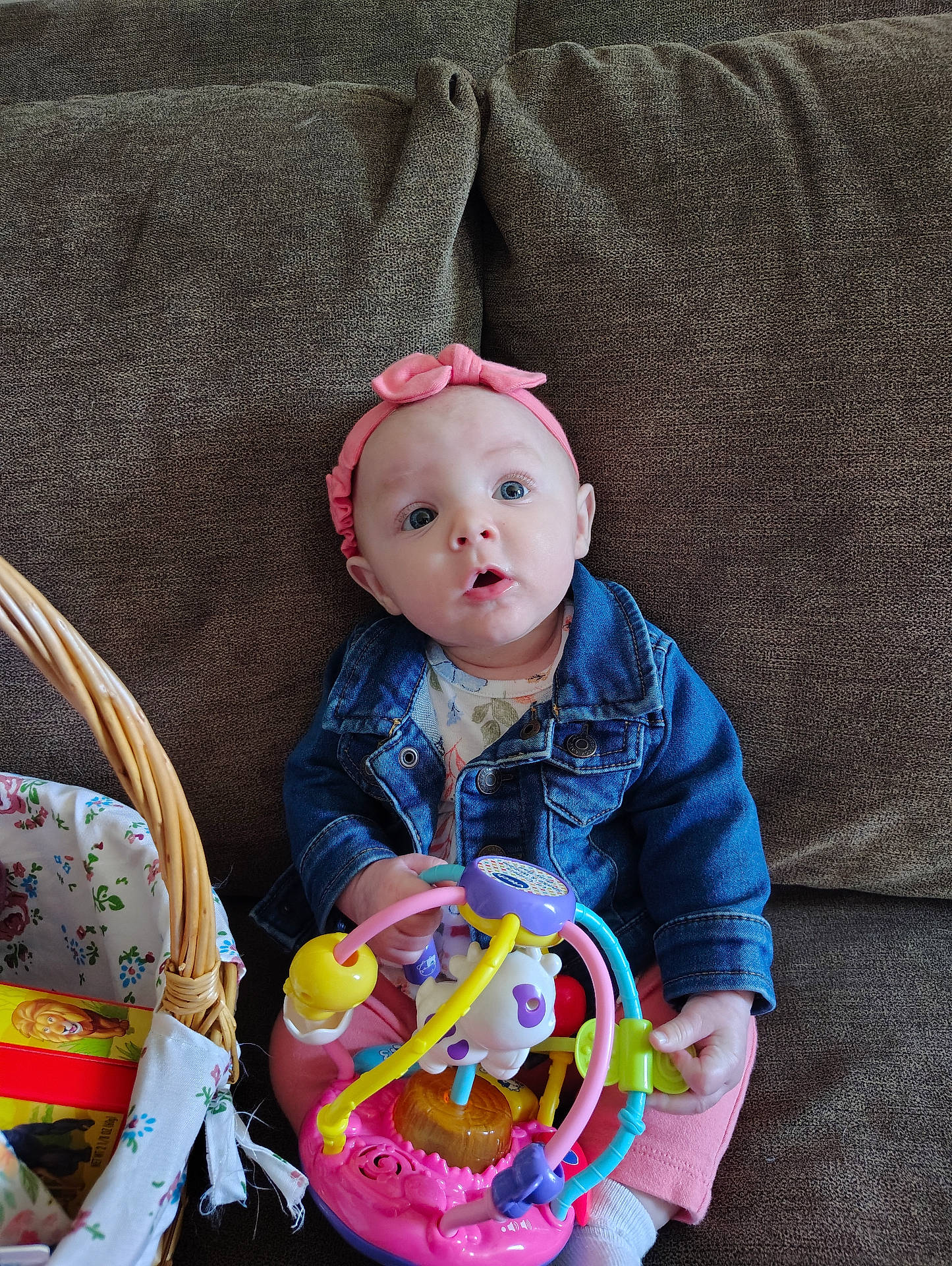 baby, basket, bed, bonnet, cap, clothing, couch, face, furniture, hat, head, homedecor, jeans, linen, pants, person, photography, portrait, rattle, toy